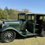 1928 Studebaker Dictator Sedan Lady Gatsby – passenger-side view with suicide doors open showing tan mohair interior, SpeedNut Classic Car Rentals.