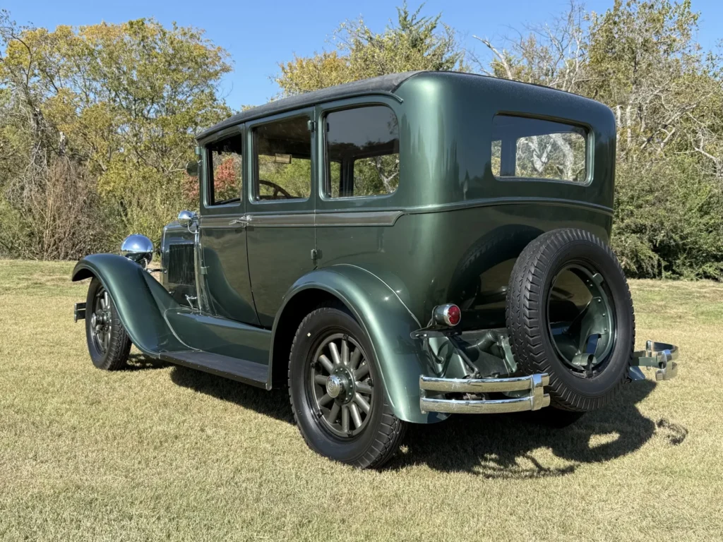 1928 Studebaker Dictator Sedan Lady Gatsby – rear driver-side view with spare tire mounted on the back, forest green exterior, SpeedNut Classic Car Rentals.